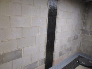 Carbon fiber reinforcement strap installed on a bowing basement wall to stabilize foundation movement