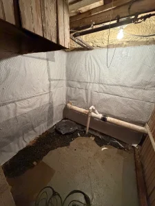 Interior French drain system and wall vapor barrier installed along basement wall in Philadelphia home