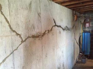 Bowing basement wall with a large horizontal crack showing structural damage caused by lateral soil pressure and foundation movement.