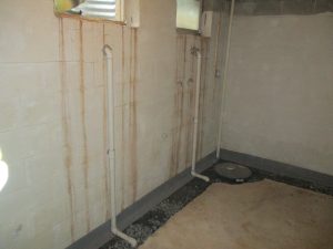 Basement drainage system and sump pump pit installed along a concrete block wall
